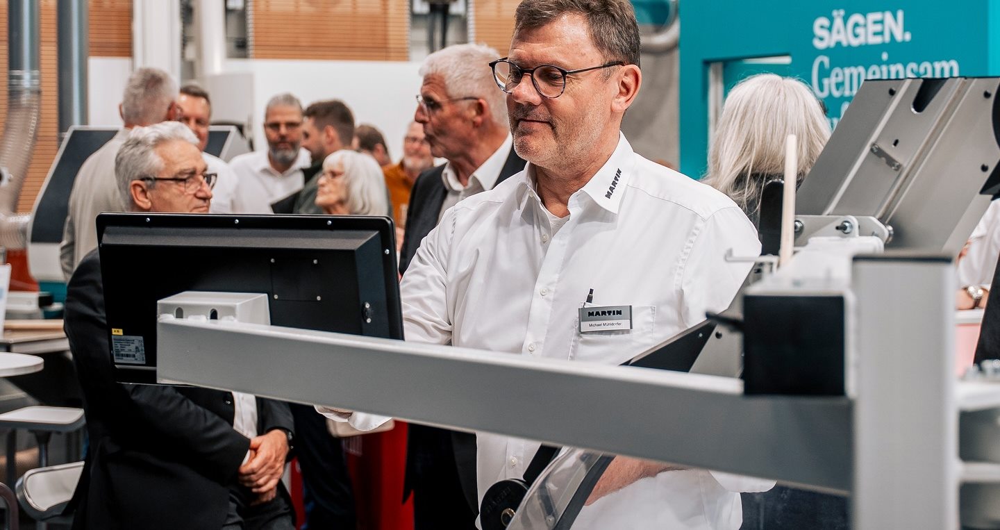 Martin-Techniker an der Bedienung einer Formatkreissäge, umringt von Besuchern