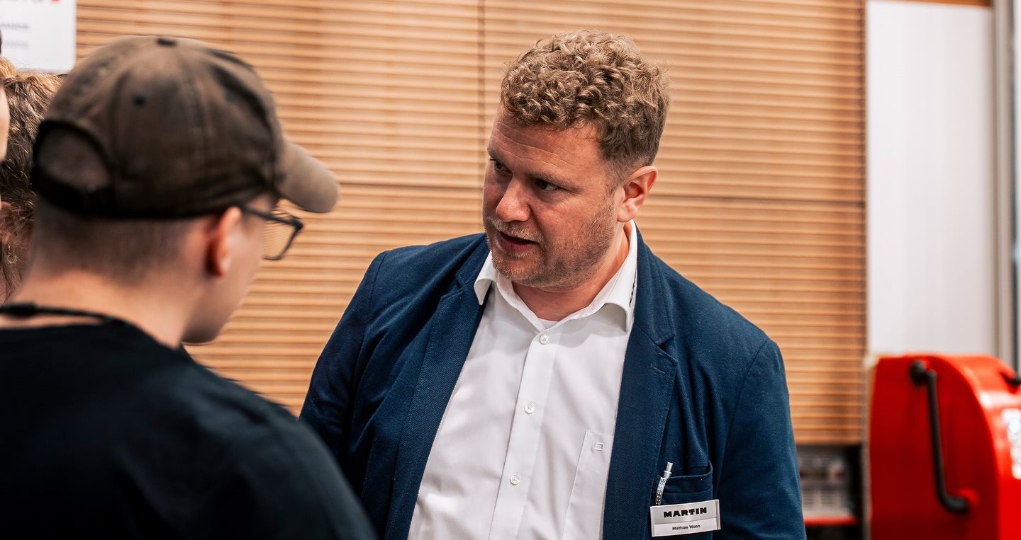 Martin-Techniker im Gespräch mit zwei Besuchern am Stand